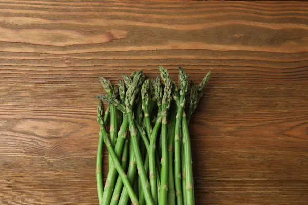 Tahta arka planda taze yeşil kuşkonmaz.