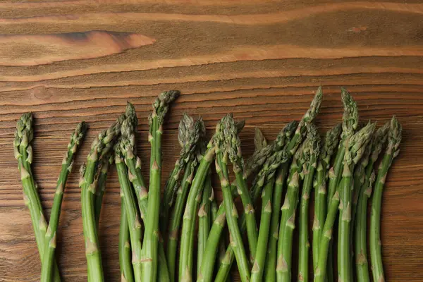 Tahta arka planda taze yeşil kuşkonmaz.