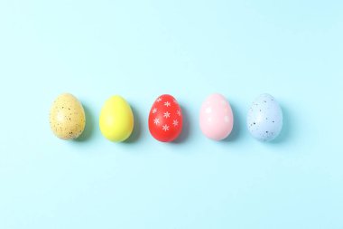 Mavi arka planda paskalya renkli yumurtalar. Üst görünüm, düz uzanma