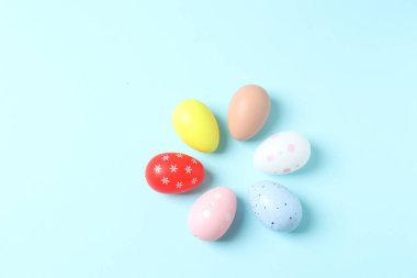 Renkli yumurta ve pastel renkli paskalya arkaplanı. Pastel mavisi üzerinde paskalya yumurtası.