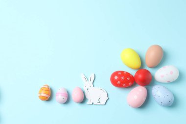 Renkli yumurtaları ve pastel renkli arka planda tavşanları olan paskalya arkaplanı. Metnin için kopyalama alanı olan üst görünüm.