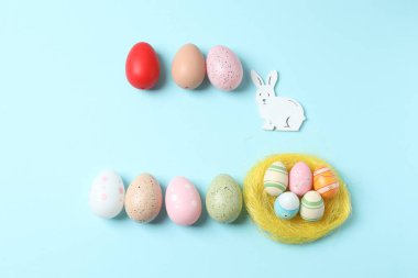 Paskalya yumurtaları ve pastel mavi arka planda tavşan kulaklı paskalya kompozisyonu. Üst görünüm, düz uzanma