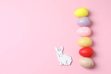 Pembe arka planda pembe paskalya tavşanı ve fotokopi alanı olan renkli yumurtaların üst görünümü