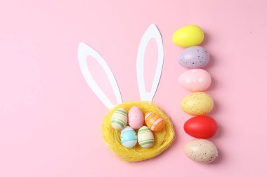 Pembe arka planda tavşan kulaklı yaratıcı Paskalya yumurtaları. en üstteki görünüm