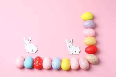 Pastel pembe arka planda renkli yumurtaları olan Paskalya tavşanı, üst manzara. Paskalya tebrik kartı.