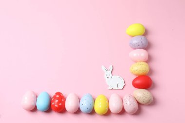 Pembe arka planda paskalya yumurtası ve tavşan.