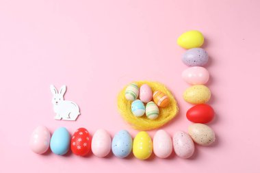 Beyaz arkaplanda renkli paskalya yumurtaları ve tavşan kulaklarının üst görünümü ve metin için kopya alanı