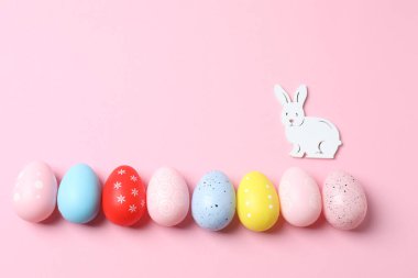 Renkli yumurta ve pastel mavi pastel arka planda tavşanlı paskalya arkaplanı. Paskalya bayramı tebrik kartı, üst görünüm