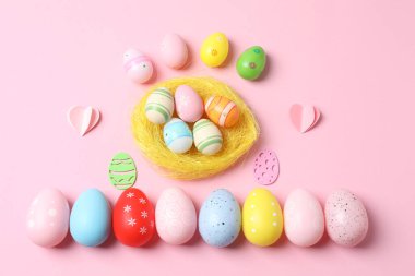 Renkli paskalya yumurtaları ve pembe arka planda tavşan kulakları.