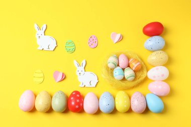 Sarı arka planda renkli paskalya yumurtaları ve tavşan