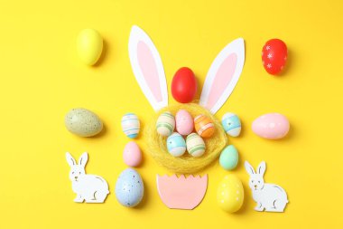 Sarı arka planda boyanmış Paskalya yumurtaları olan Paskalya tavşanı.