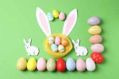 sevimli tavşan kulaklı yaratıcı kompozisyon ve yeşil arka planda paskalya yumurtaları.