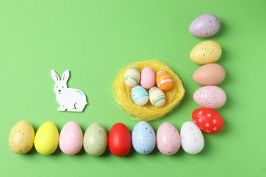 Renkli paskalya yumurtaları ve yeşil arka planda tavşanlı yaratıcı kompozisyon, metin için boşluk ile üst görünüm