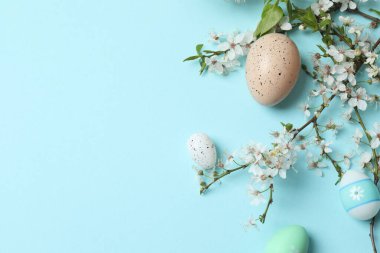 Yuvadaki paskalya yumurtaları ve pastel yeşil arka plandaki bahar çiçekleri