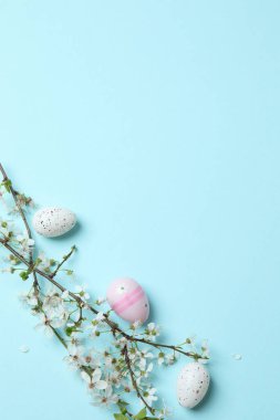Mavi arka planda paskalya yumurtaları ve bahar çiçekleri dalları, fotokopi alanının üst görüntüsü. Paskalya tebrik kartı, afiş, poster.