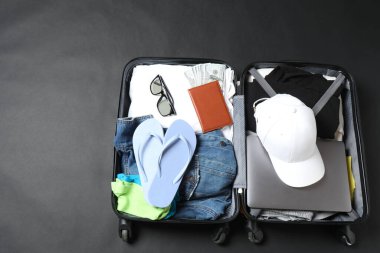 Elbiseli bavul, gri arka planda seyahat aksesuarları