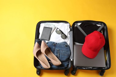 Bavullu ve arka planda kıyafetleri olan bir kadın.