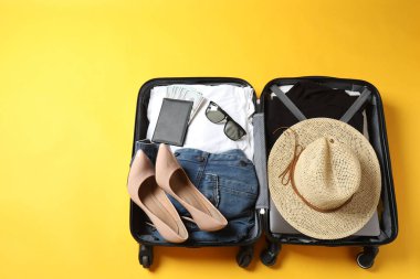 Yaz tatili konsepti. Çantanın üst görüntüsü ve parmak arası terlikli şapka, sarı güneş gözlüğü ve sarı arka planda pasaportlu şapka.