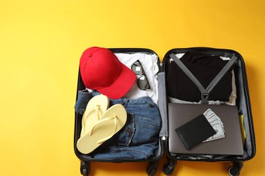 Renkli arka planda seyahat için giysileri olan bavul