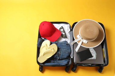 Hafif arkaplanda seyahat aksesuarları olan bavul