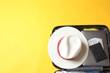 Çantalı seyahat konsepti, pasaport, kamera, şapka, gözlük, pasaport, uçak ve güneş gözlüğü sarı arka planda. Üst Manzara. Boşluğu kopyala