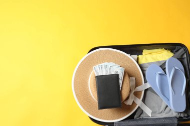 Gezgin şapkası, pasaportlu bavul, kamera ve sarı arka planlı pasaport, kopyalama alanı