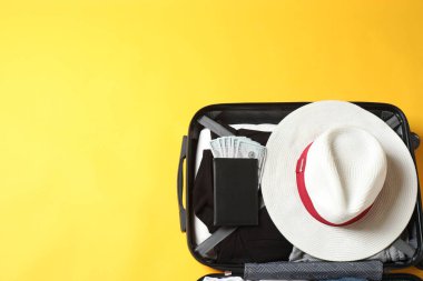 Şapkalı, güneş gözlüklü ve pasaportlu bir seyahat çantası.