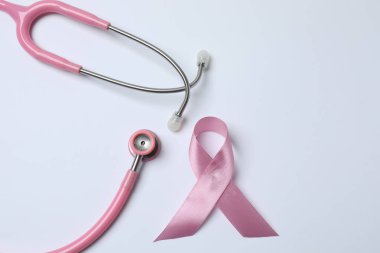 Beyaz pembe arka planda steteskop, üst manzara. Göğüs kanseri farkındalığı