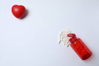 Beyaz arka planda kalp şeklinde kırmızı haplar..