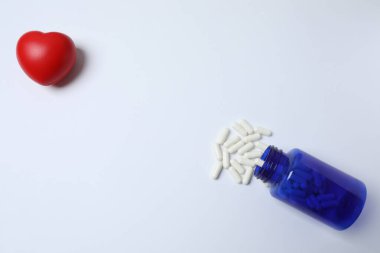 Kalp şeklinde, beyaz arka planda haplar ve kapsüller. Sağlık, tıbbi konsept.