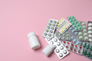 Pembe arka planda ilaç ve haplar.