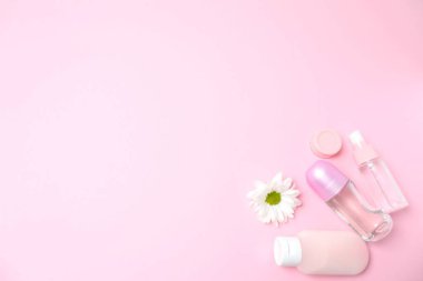 Çiçekli kozmetik şişesi ve pastel pembe arka planda mesaj için boş alan. düz yatış, üst görünüm