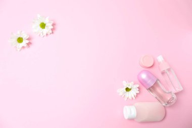 Kozmetik krem, pastel renkli arka planda pembe çiçek ve fotokopi alanı. düz yatış, üst görünüm.