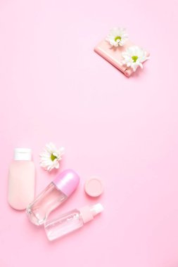 Kozmetik şişesi ve pembe arka planda pembe gül çiçekleri. düz yatak, güzellik, spa, vücut bakımı konsepti.