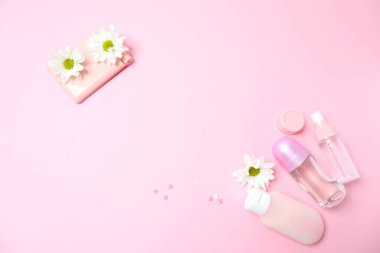 Pastel pembe arka planda çiçekli kozmetik ürünleri