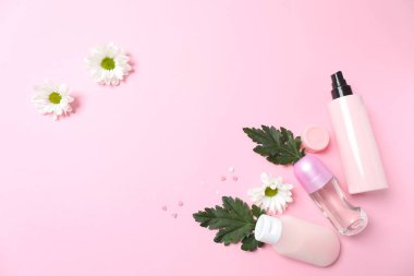 Çiçek yapraklı kozmetik şişesi ve pembe arka planda bir şişe. Düz yat. Boşluğu kopyala