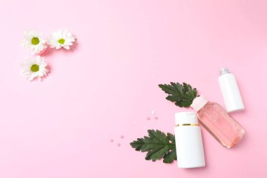 Renkli arkaplanda bir şişe parfüm ve çiçek kompozisyonu