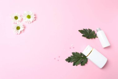 düz bir parfüm ve pembe arka planda çiçekler olan boş bir şişe..