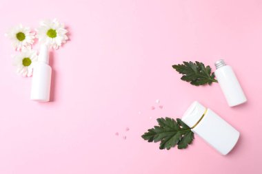 Çiçekli beyaz şişe ve pembe arka planda parfüm. en üstteki görünüm