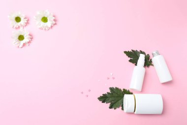 Boş kozmetik ürünleri ve pembe arka planda bir şişe kremayla yatıyordu..