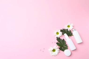 Pembe arka planda pembe çiçekli beyaz bir parfüm şişesi..