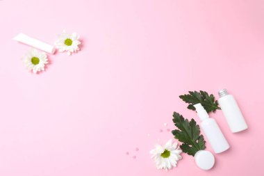 Beyaz çiçekli beyaz şişenin üst görüntüsü ve pembe arka planda boş alan