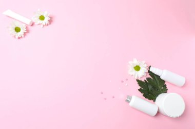 Güzellik ürünleri, çiçekler ve pembe arka planda yapraklar. Spa konsepti. Üst görünüm, düz görünüm, kopyalama alanı
