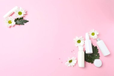 Beyaz kozmetik krem, gül, krem ya da yüz kremi pembe arka planda bir çiçekle.