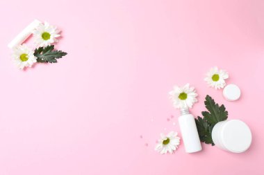 Boş kozmetik krem ya da kozmetik krem düzlüğü, pastel arka planda çiçekler ve yapraklar. en üstteki görünüm.