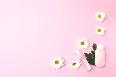 Doğal kozmetik şişeleri, papatyalar ve pastel arka planda çiçekler. Metin için boşluk