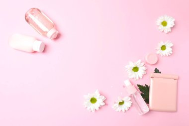 Kozmetik ürünleri ve pembe arka planda çiçeklerle yatıyordu. güzellik konsepti
