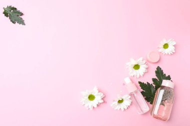 Pembe pastel arka planda pembe çiçek ve kozmetik.