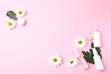 Pembe arka planda çiçekli kozmetik ürünleri