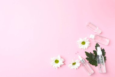 Beyaz arka planda pembe çiçekli kozmetik şişeler. kopyalama alanı. Düz yat. en üstteki görünüm
